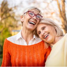 Two older adults standing close together outdoors